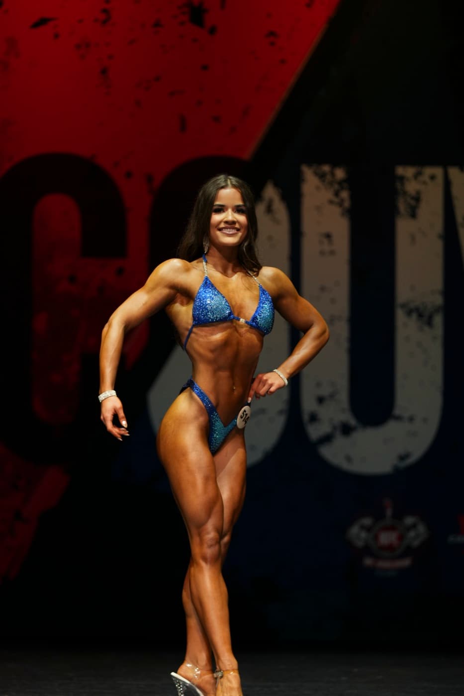 Maddie posing on stage in her blue competition suit